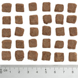 Brown, square food pieces approximately 1 cm in size, shown next to a ruler for size reference.