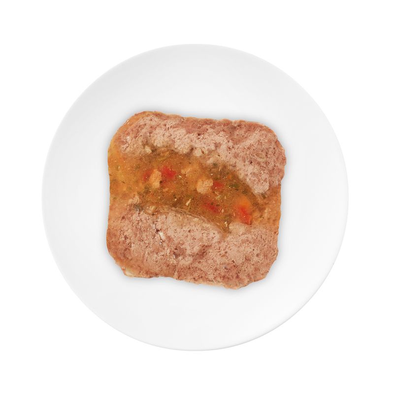 Close-up of a piece of wet food with meat and vegetables on a white plate.